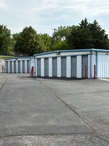 Rows of white storage buildings with blue roll-up doors and mountain views on a clear day at American Mini Storage in Staunton, VA