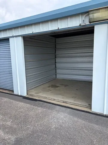 Open roll-up door on a clean ground-level drive-up storage unit with pavement right at the doorway at American Mini Storage in Staunton, VA